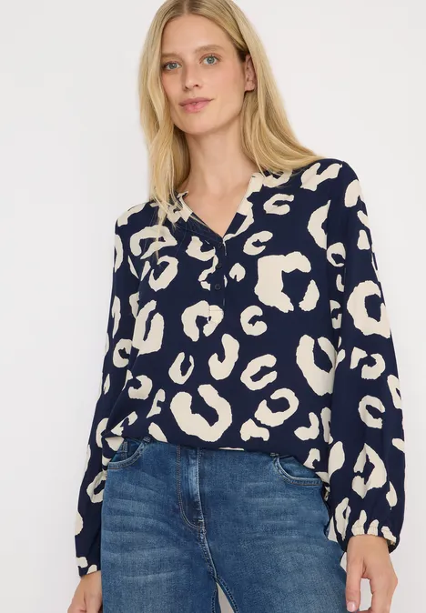 Frau mit blauer Bluse im Leopardenmuster und Jeans.